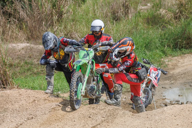 Riders helping each other with a dirt bike on the trail
